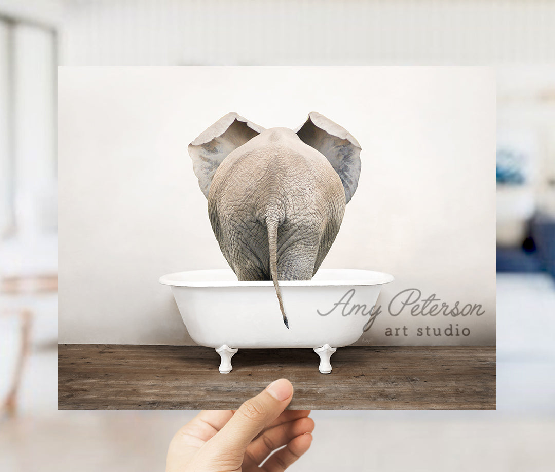 a person holding up a picture of an elephant in a bathtub