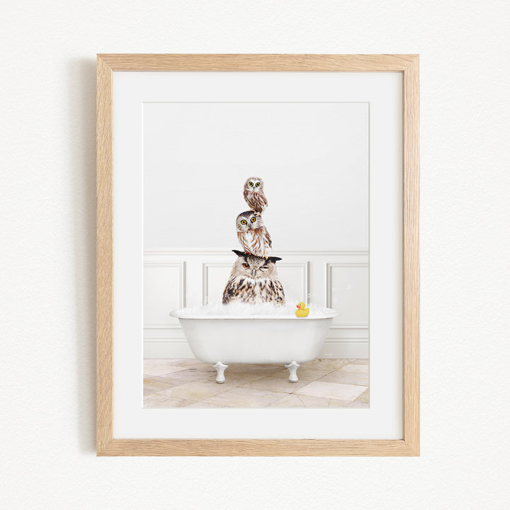 A framed image depicting a white bathtub filled with water, with a stack of owls sitting on top of it.