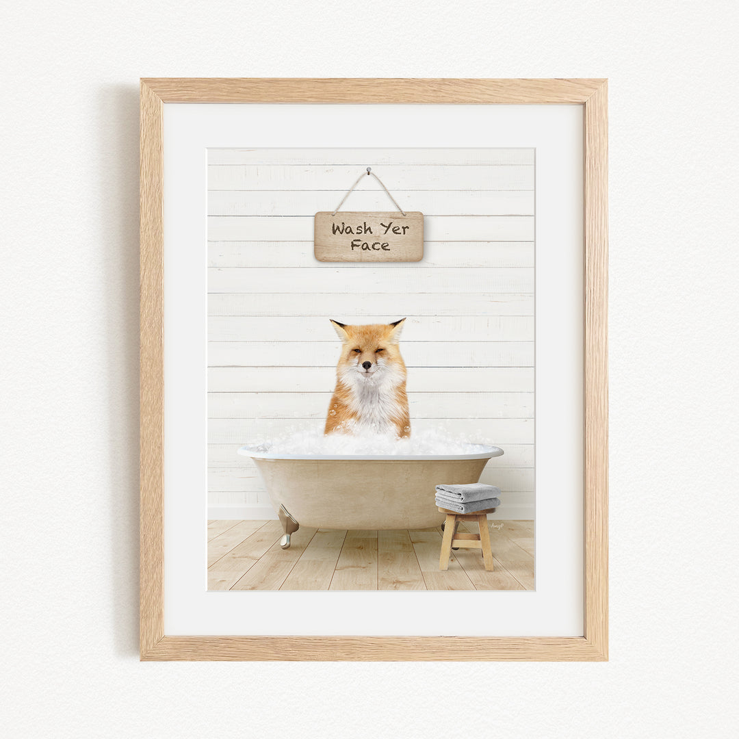 A framed image depicting a fox sitting in a bathtub, with a sign above that reads "Wash Your Face".