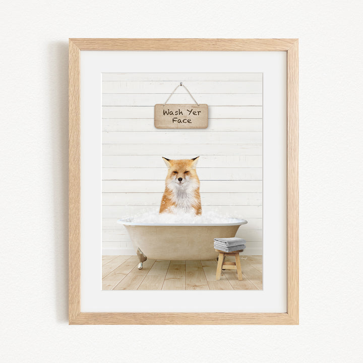 A framed image depicting a fox sitting in a bathtub, with a sign above that reads "Wash Your Face".
