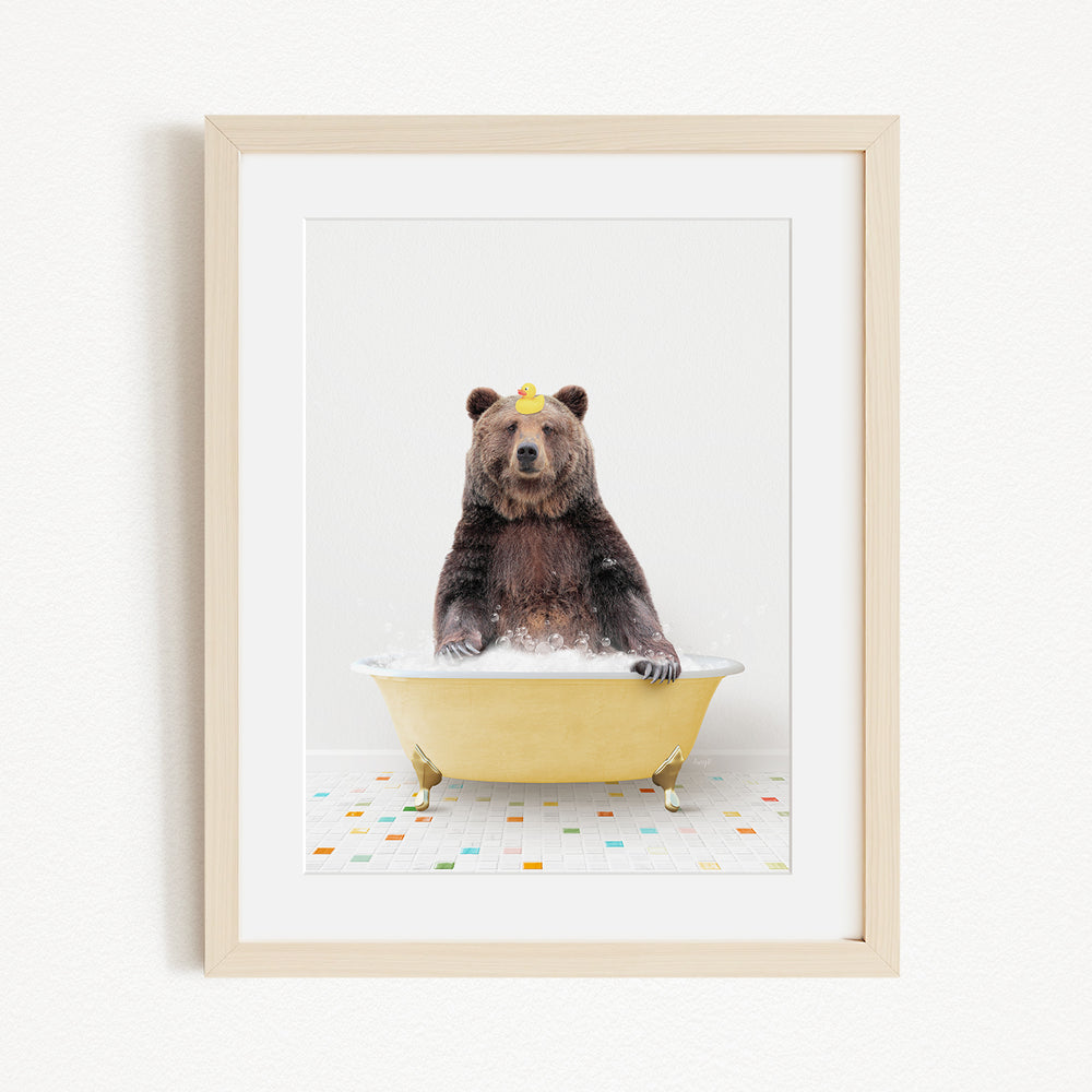 A brown bear sitting in a yellow bathtub filled with bubbles, with a yellow rubber duck floating on the water.