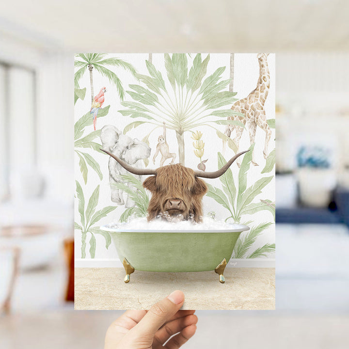 A hand holds up a framed print featuring an illustration of a horned animal, likely a yak or a cow, sitting in a bathtub surrounded by tropical foliage.