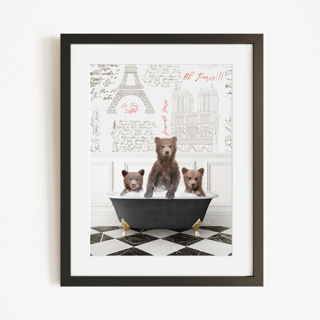 A framed image depicting three brown bears sitting in a bathtub, with a drawing of the Eiffel Tower in the background.