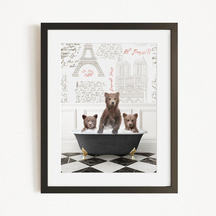 A framed image depicting three brown bears sitting in a bathtub, with a drawing of the Eiffel Tower in the background.