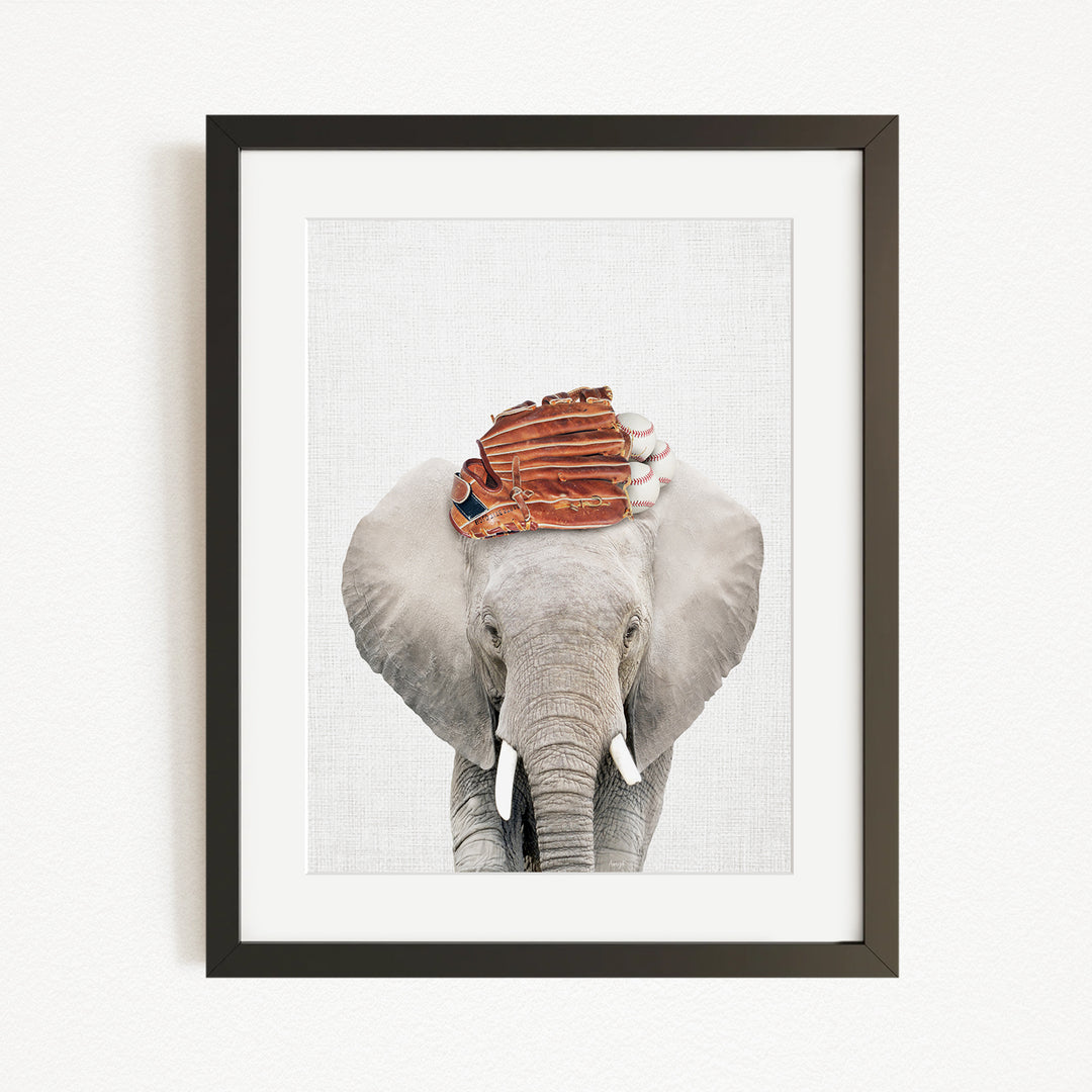 A framed image of an elephant wearing a baseball glove on its head.