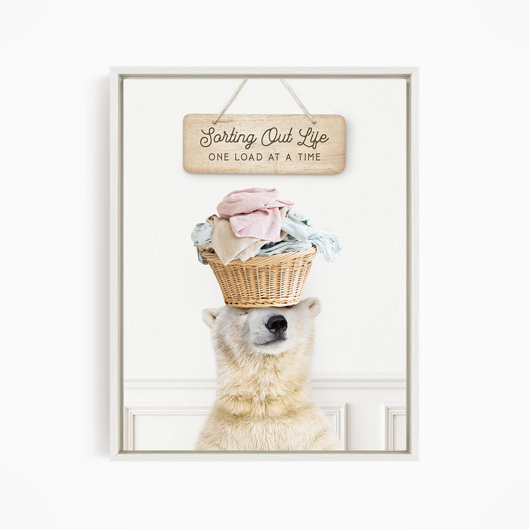 A polar bear balancing a basket of laundry on its head, with a sign above that says "Sorting Out Life One Load at a Time".
