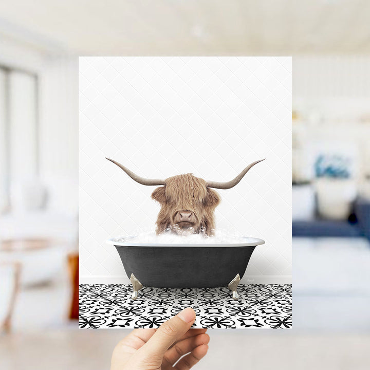 A hand holds up a framed image of a horned animal, likely a yak or a yak, sitting in a bathtub filled with water.