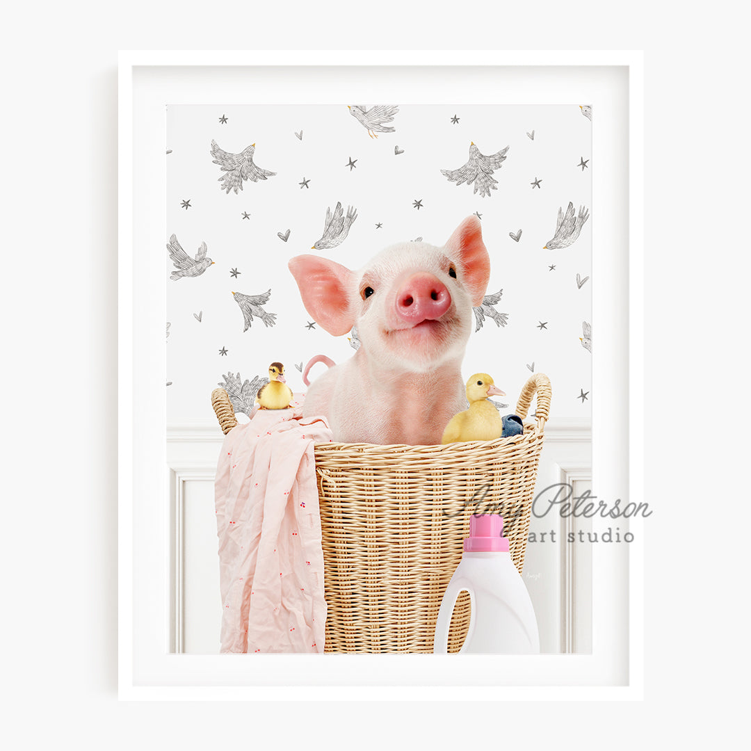 a little pig sitting in a basket with a pink blanket