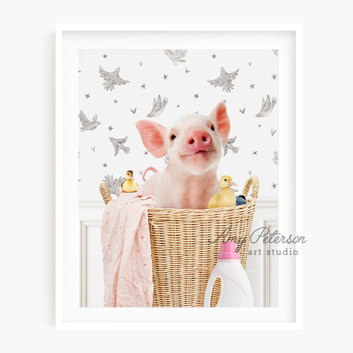 a little pig sitting in a basket with a pink blanket