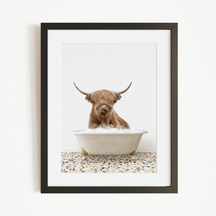A Highland cow with long horns is sitting in a white bathtub filled with water, creating a whimsical and playful scene.