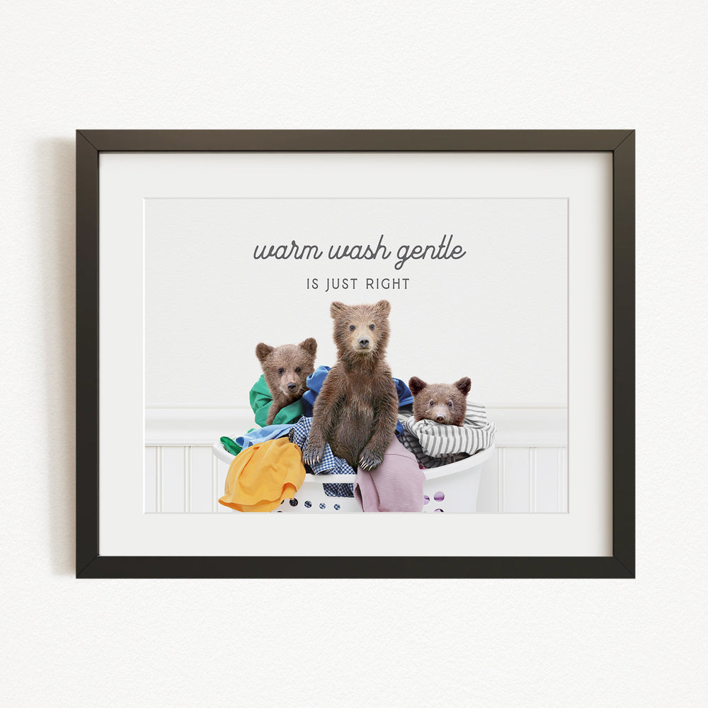 A framed image depicting three bears sitting in a laundry basket, with the text "Warm wash gentle is just right" written above them.