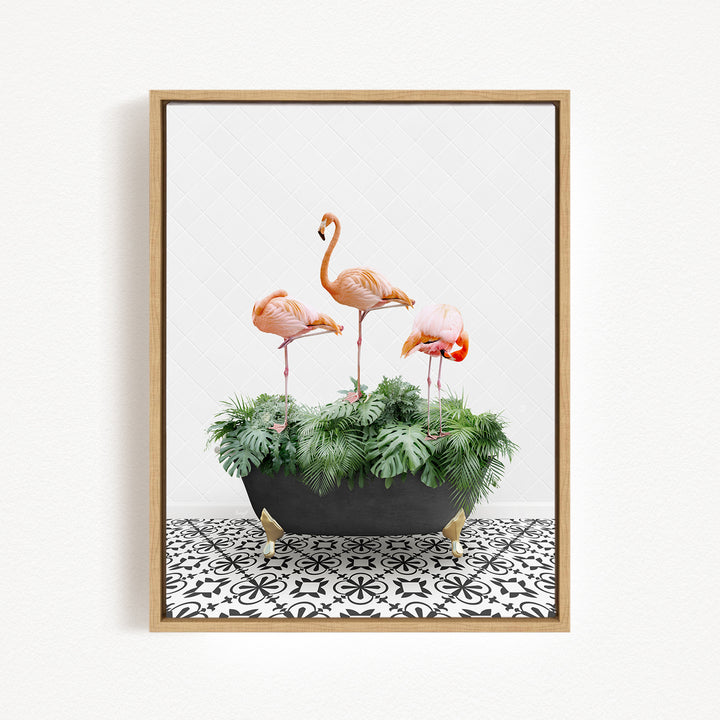 A framed image of three pink flamingos standing in a black planter filled with green plants, placed on a black and white patterned floor.