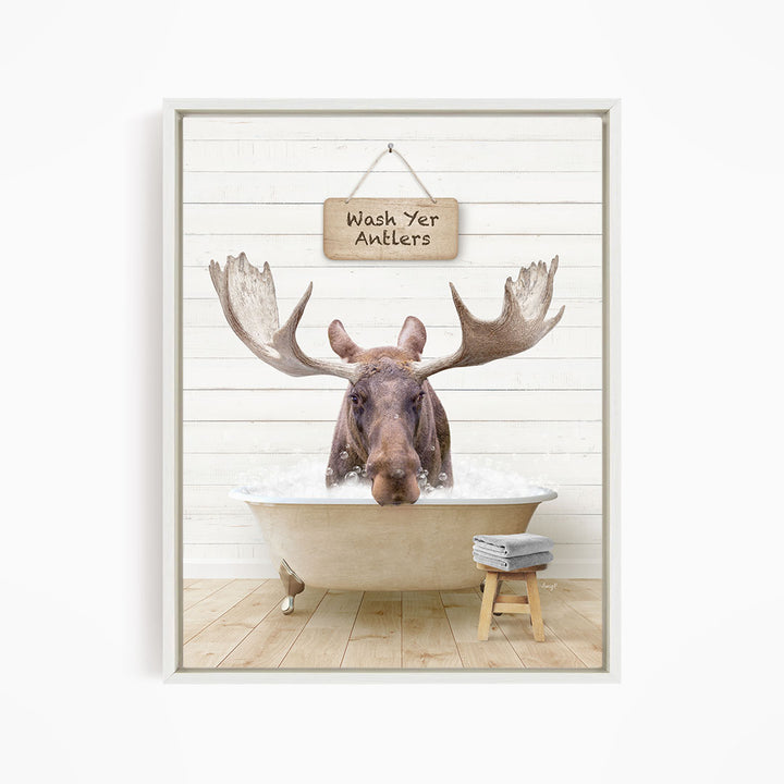 A moose is sitting in a bathtub filled with water, with a sign above it that says "Wash Yer Antlers".