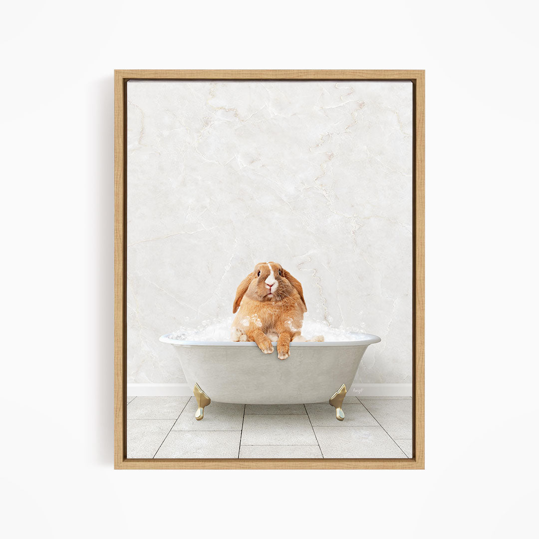 A brown rabbit sitting in a white bathtub filled with bubbles, looking up at the camera.