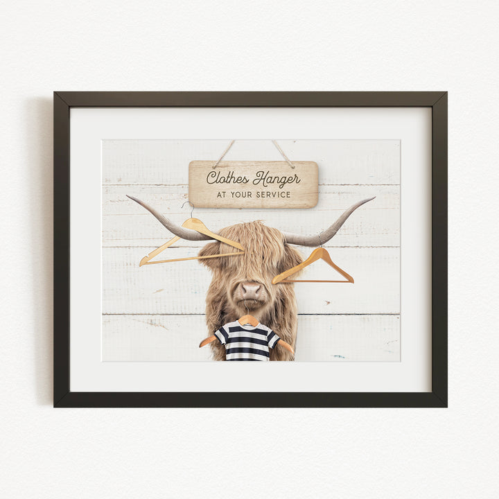 A framed image depicting a large, furry animal with a sign that reads "Clothes Hanger at your service" in front of it.