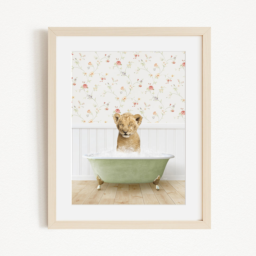 A young lion cub sitting in a green bathtub filled with water, with a floral wallpaper in the background.