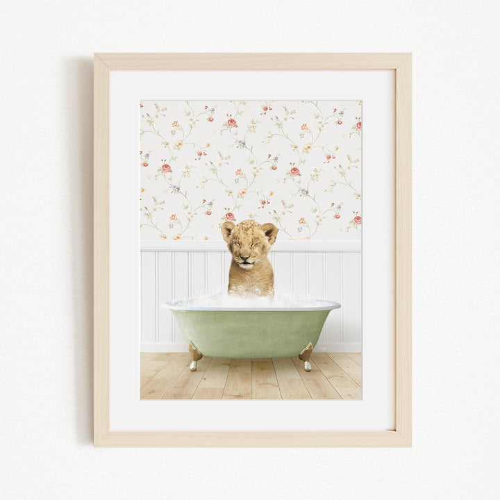 A young lion cub sitting in a green bathtub filled with water, with a floral wallpaper in the background.
