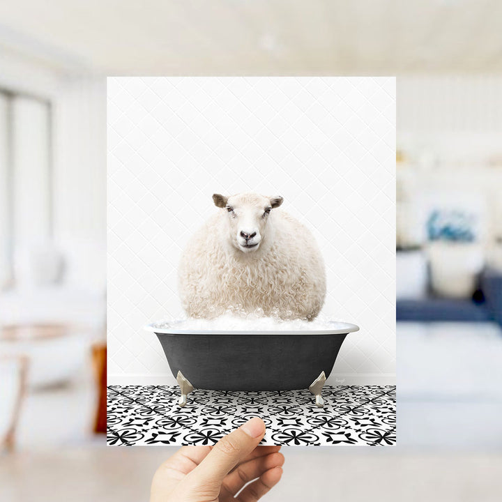 A fluffy white sheep sits in a black bathtub filled with bubbles, surrounded by a black and white patterned floor.