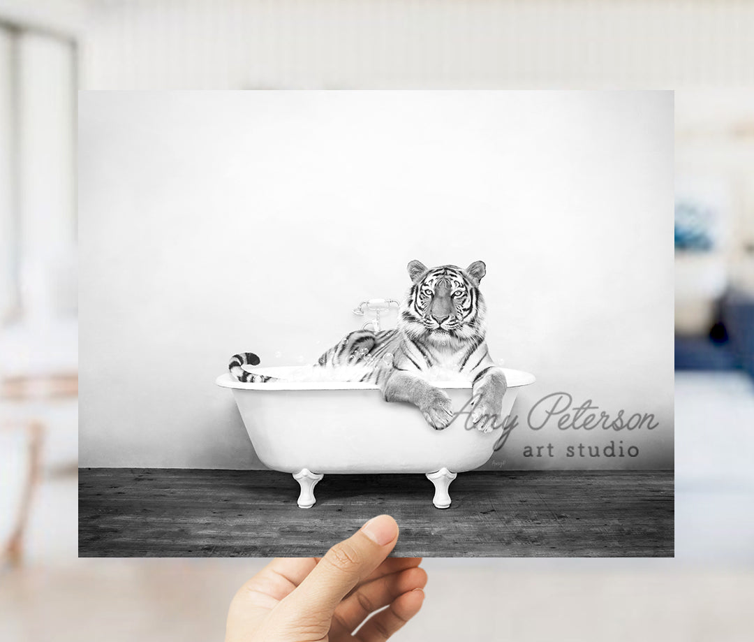 a hand holding up a black and white photo of a tiger in a bathtub