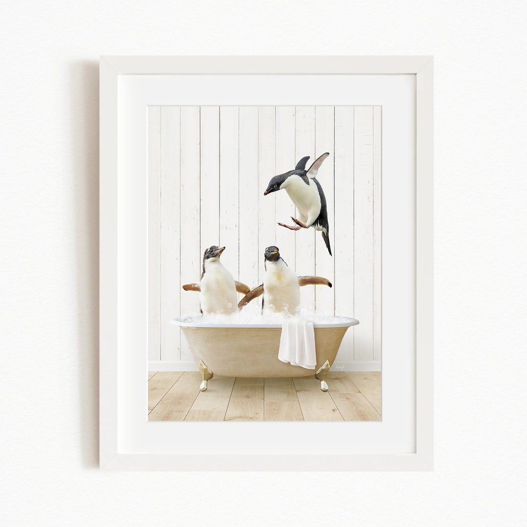 A framed image depicting two penguins sitting in a bathtub, with one penguin standing on the edge of the tub and another penguin sitting inside the tub.
