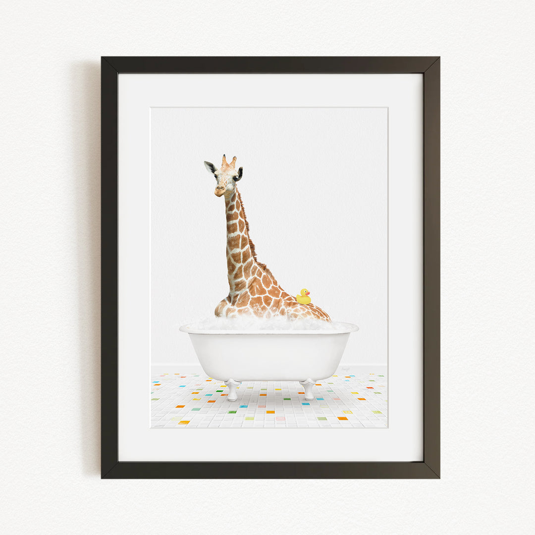 A giraffe is sitting in a white bathtub filled with bubbles, with a yellow rubber duck floating on the water.