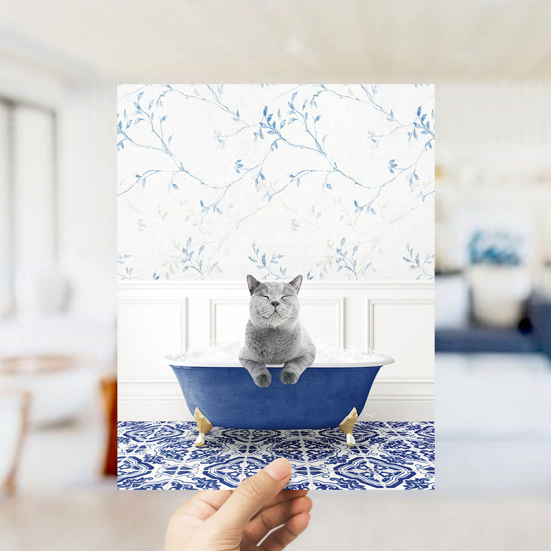 A gray cat sitting in a blue bathtub with a floral pattern on the wall behind it.