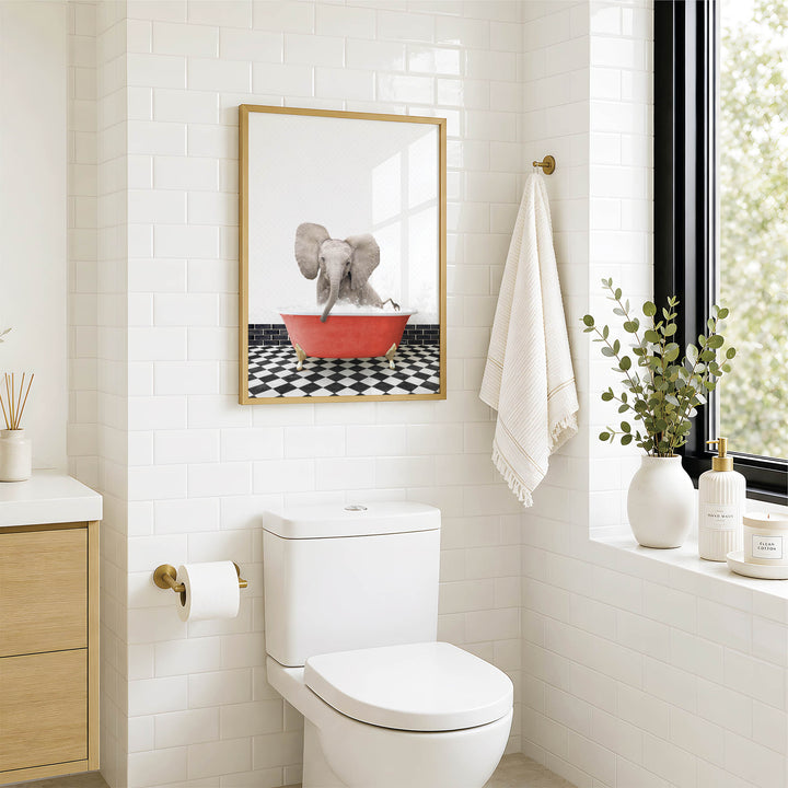 a bathroom with a white toilet, a framed picture of an elephant in a red bathtub, and a towel hanging on the wall.
