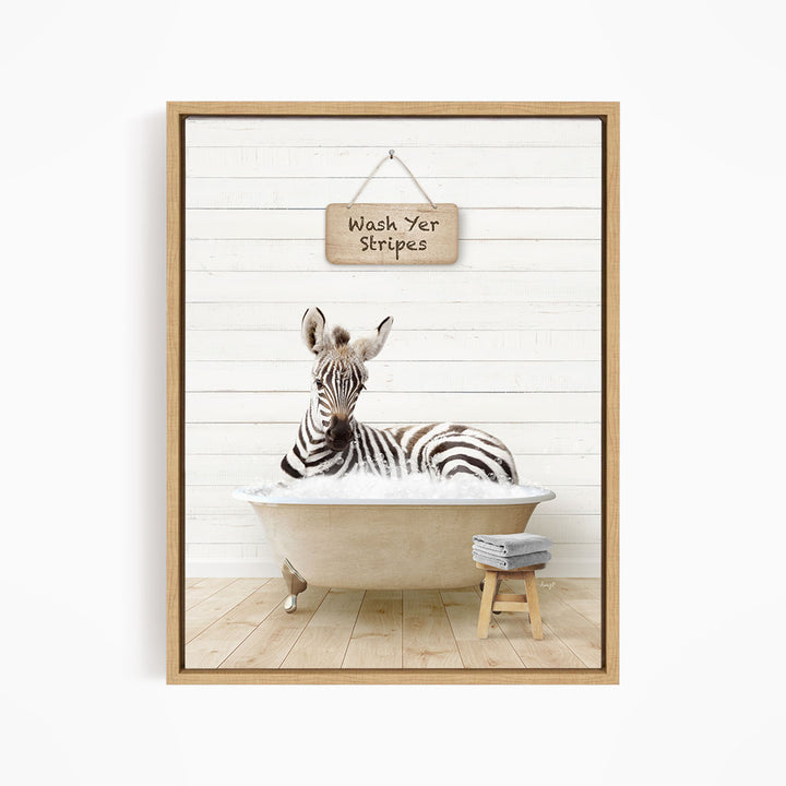 A zebra is sitting in a bathtub, with a sign above it that says "Wash Yer Stripes".