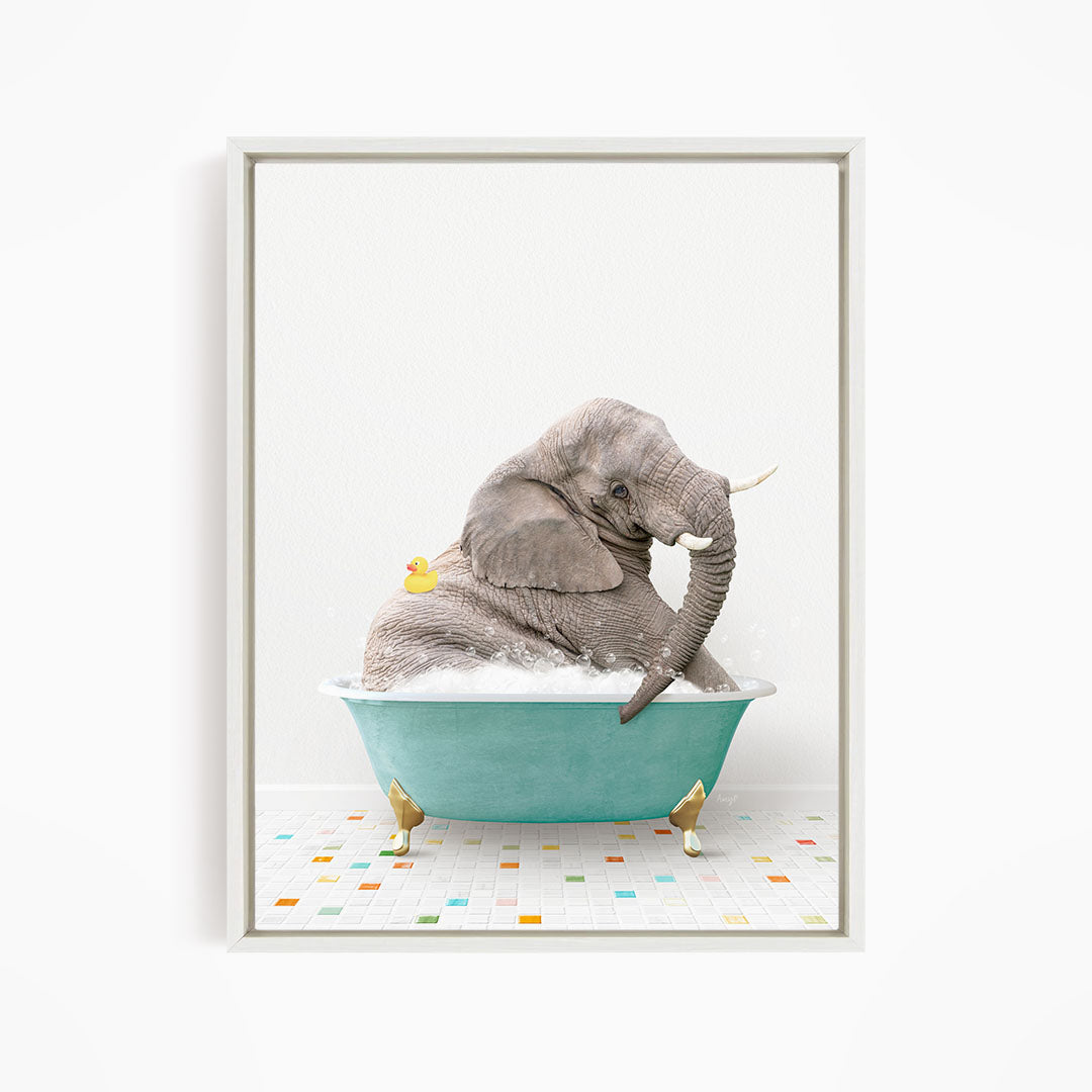 A gray elephant is sitting in a blue bathtub, with a yellow rubber duck floating on its back.