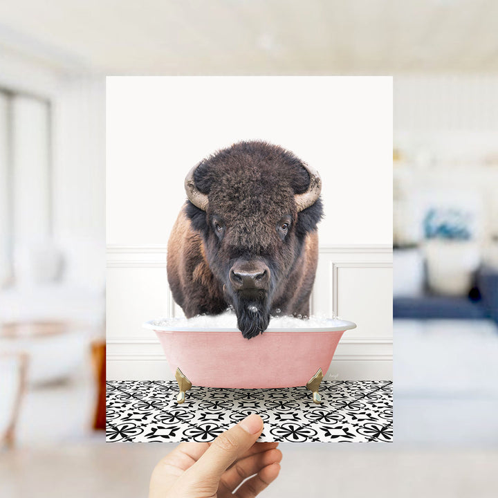 A large, furry bison with horns is standing in a pink bathtub filled with bubbles, creating a whimsical and unexpected scene.