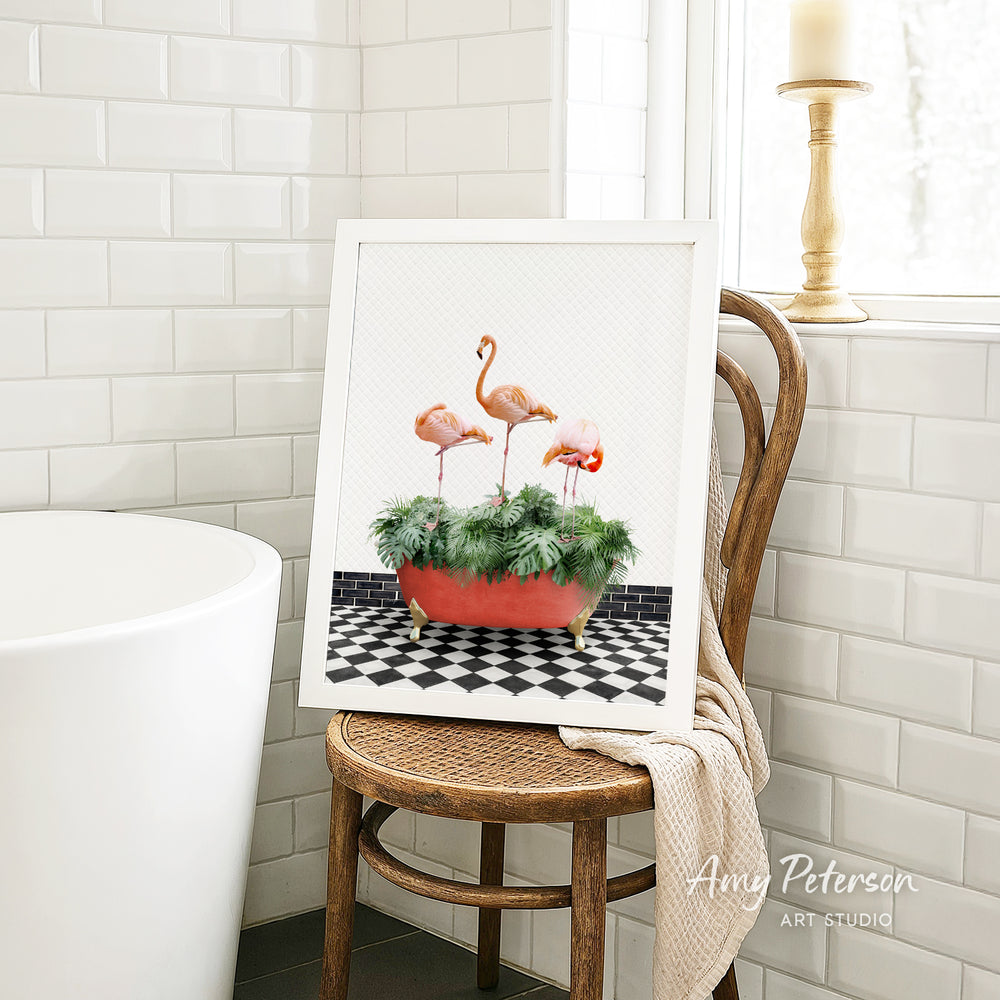 A framed image of three flamingos standing in a red bathtub filled with green plants, placed on a wooden chair in a bathroom setting.