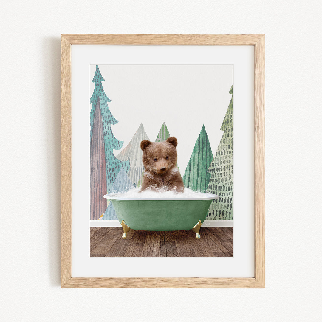 A small brown bear is sitting in a green bathtub, surrounded by a forest scene with trees and a snowy landscape.