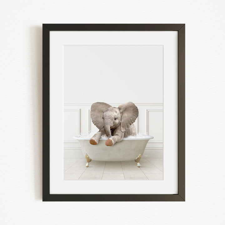A baby elephant sitting in a white bathtub, with its large ears spread out and its trunk raised.