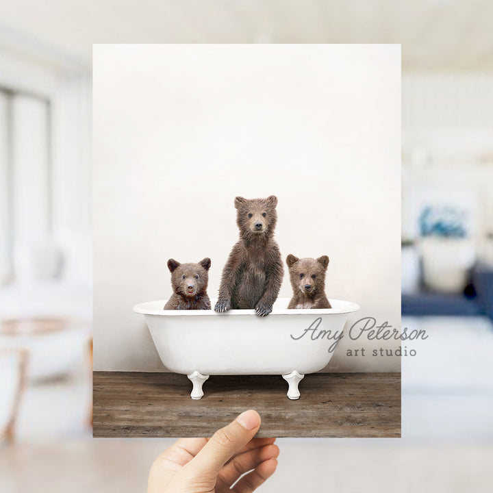 a hand holding a card with three bears in a bathtub