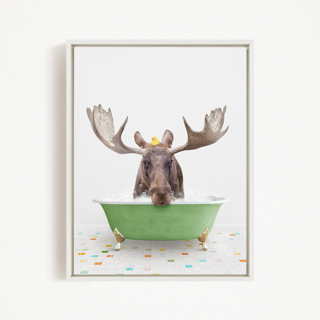 A moose with large antlers is sitting in a green bathtub filled with water, with a rubber duck floating on its head.
