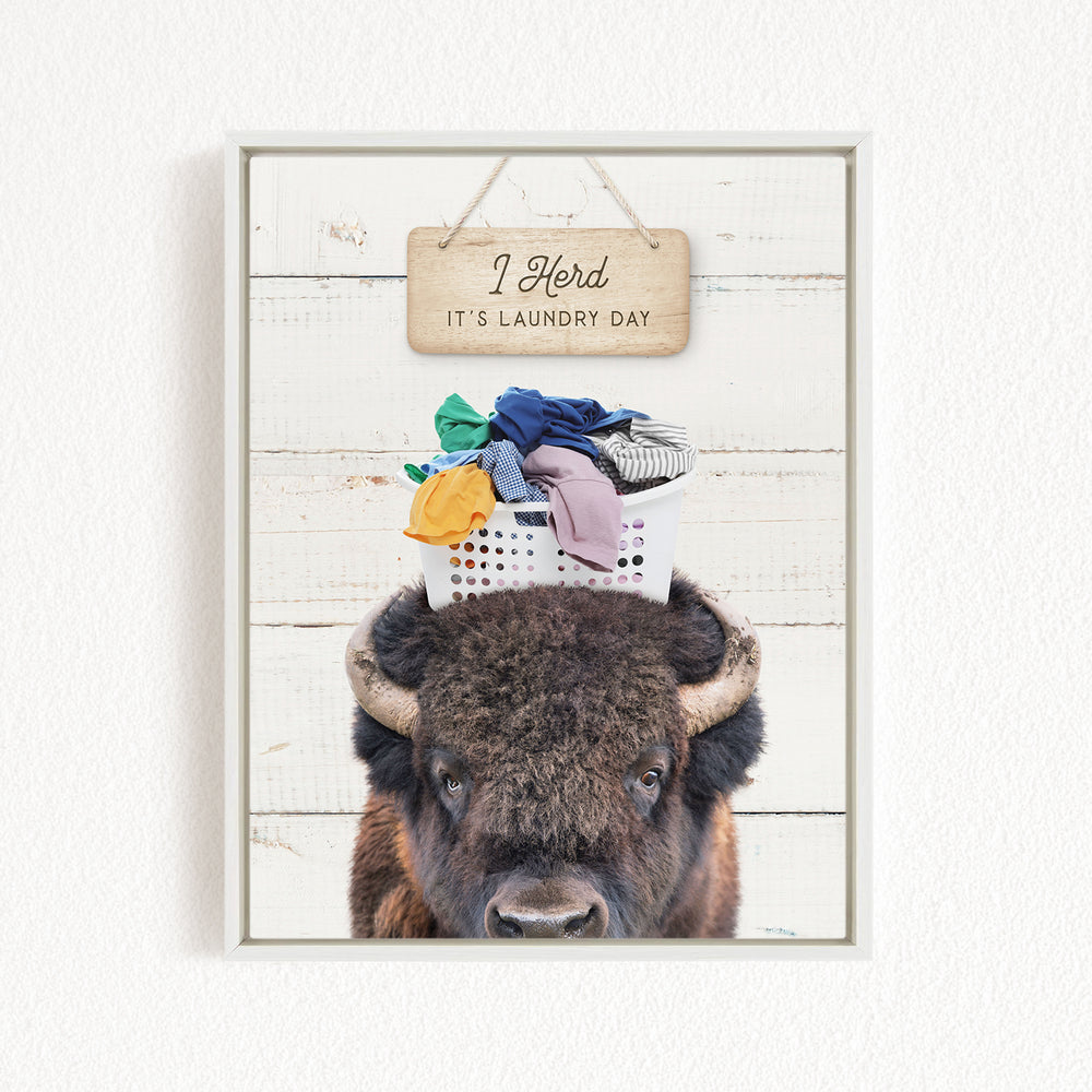 A buffalo with a basket of laundry on its head, accompanied by a wooden sign that says "It's laundry day".