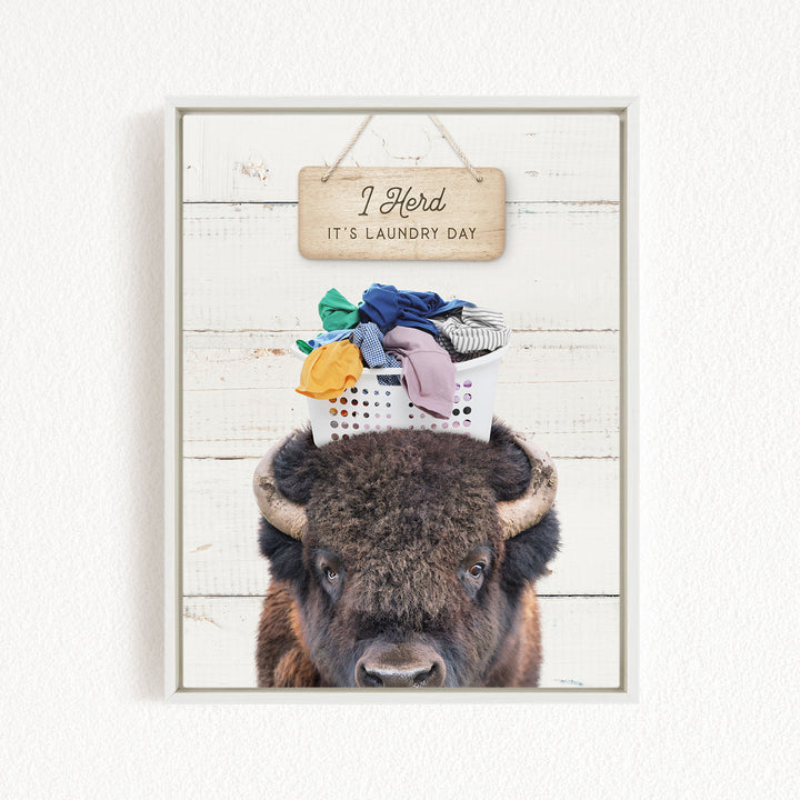 A buffalo with a basket of laundry on its head, accompanied by a wooden sign that says "It's laundry day".