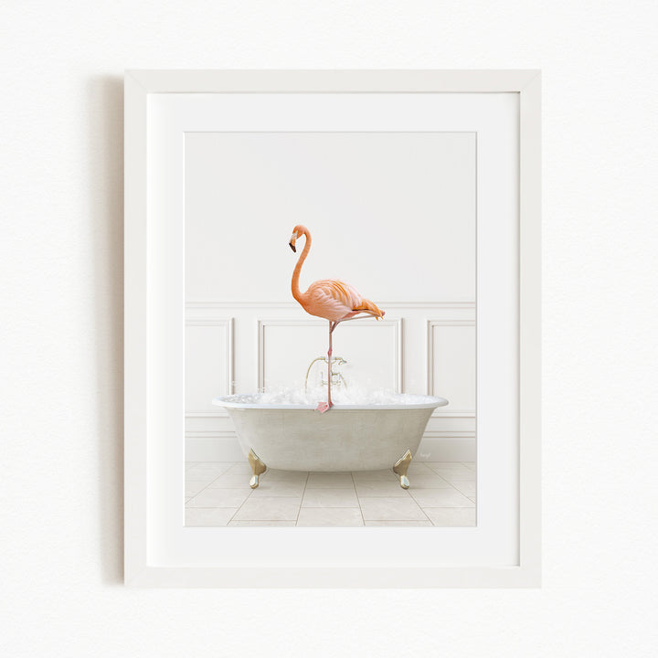 A framed image of a pink flamingo standing on the edge of a white bathtub filled with water.