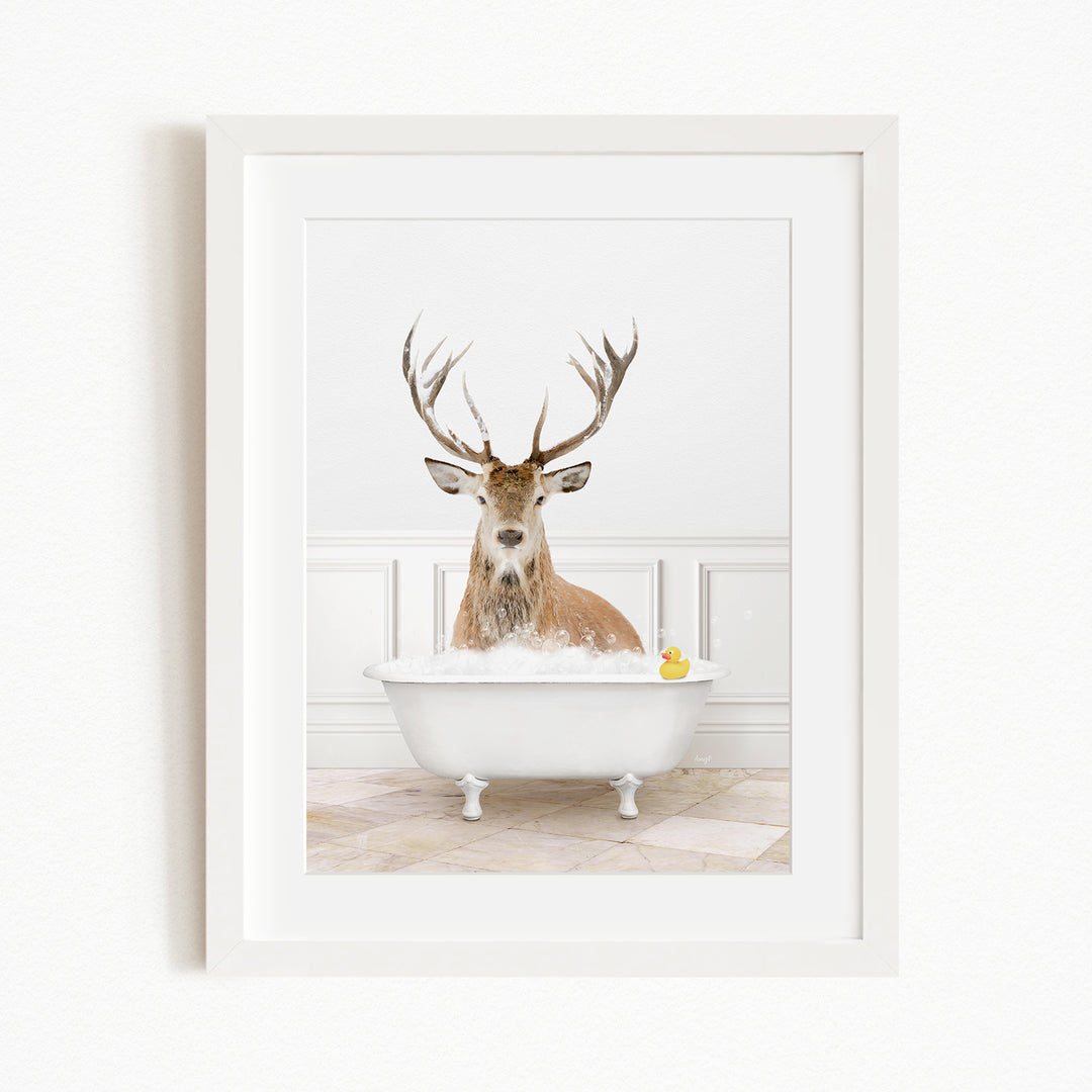 A deer with large antlers is sitting in a white bathtub filled with water, with a yellow rubber duck floating in the tub.