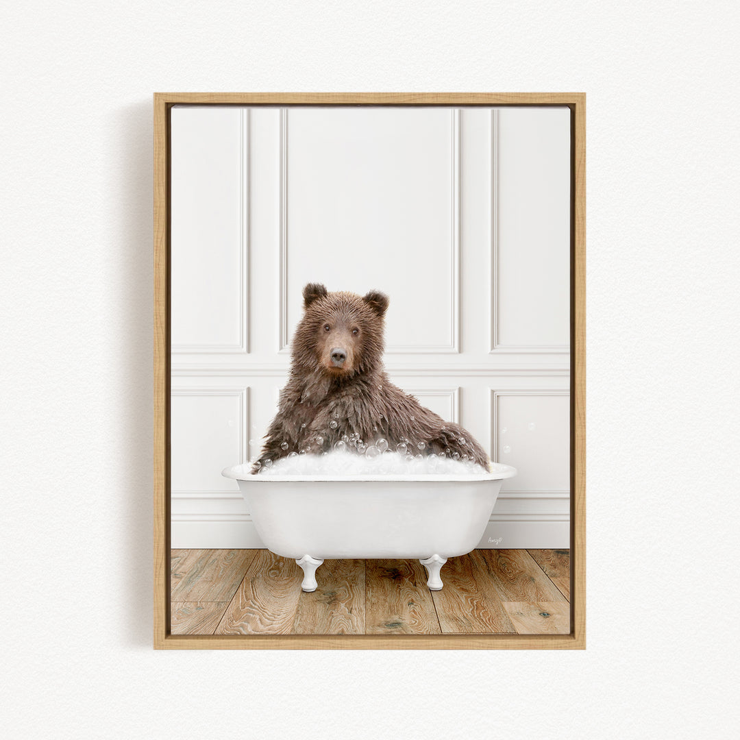 A brown bear sitting in a white bathtub filled with bubbles, looking directly at the camera.