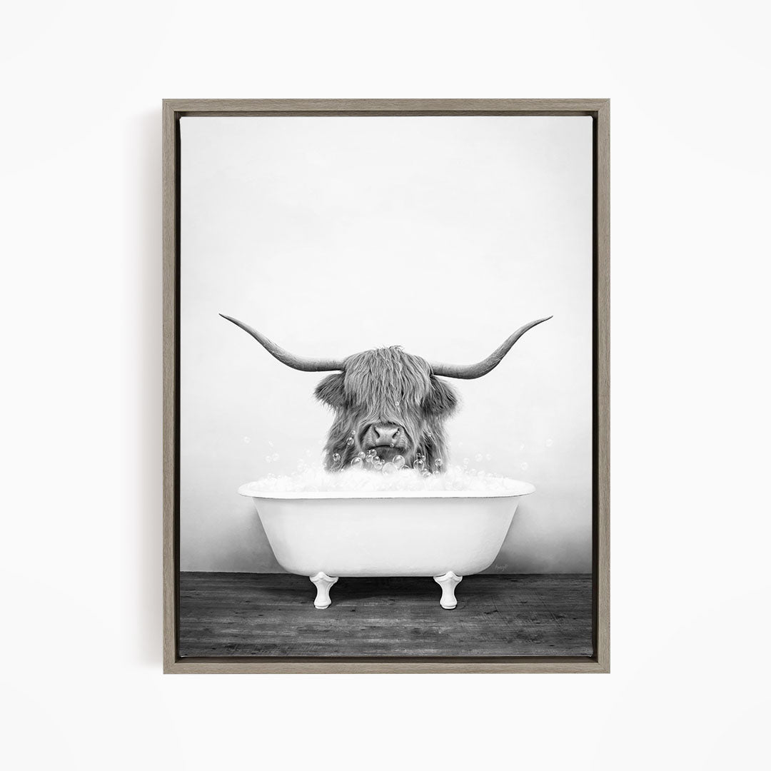 A black and white image of a horned animal, possibly a yak or a bison, sitting in a white bathtub filled with water.