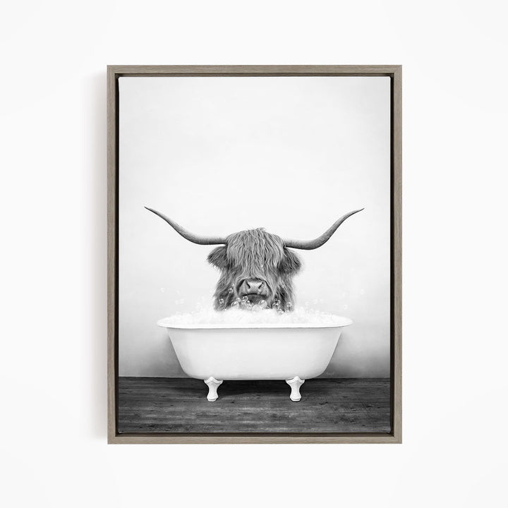 A black and white image of a horned animal, possibly a yak or a bison, sitting in a white bathtub filled with water.