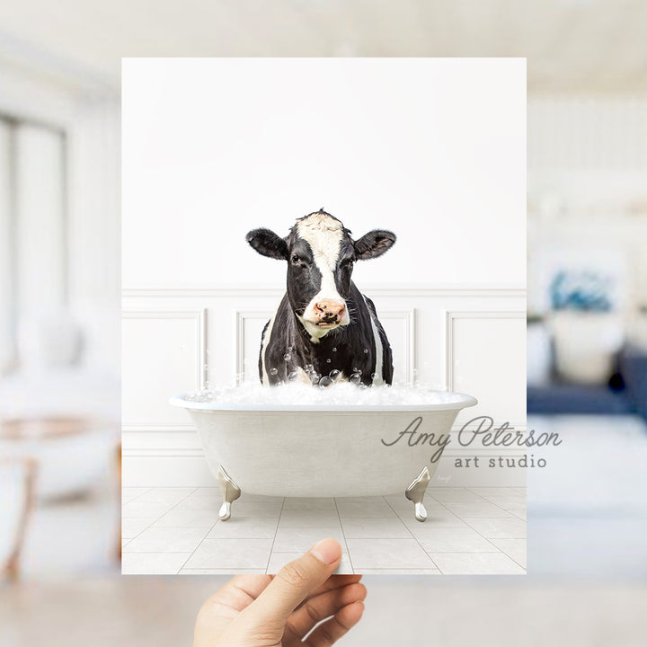 a hand holding up a card with a picture of a cow in a bathtub