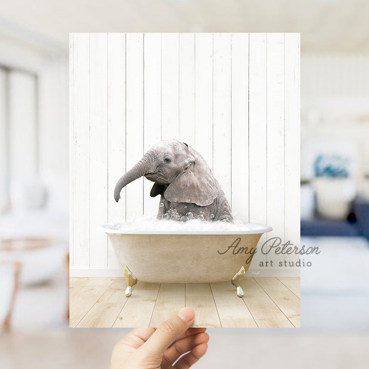 a hand holding up a picture of an elephant in a bathtub