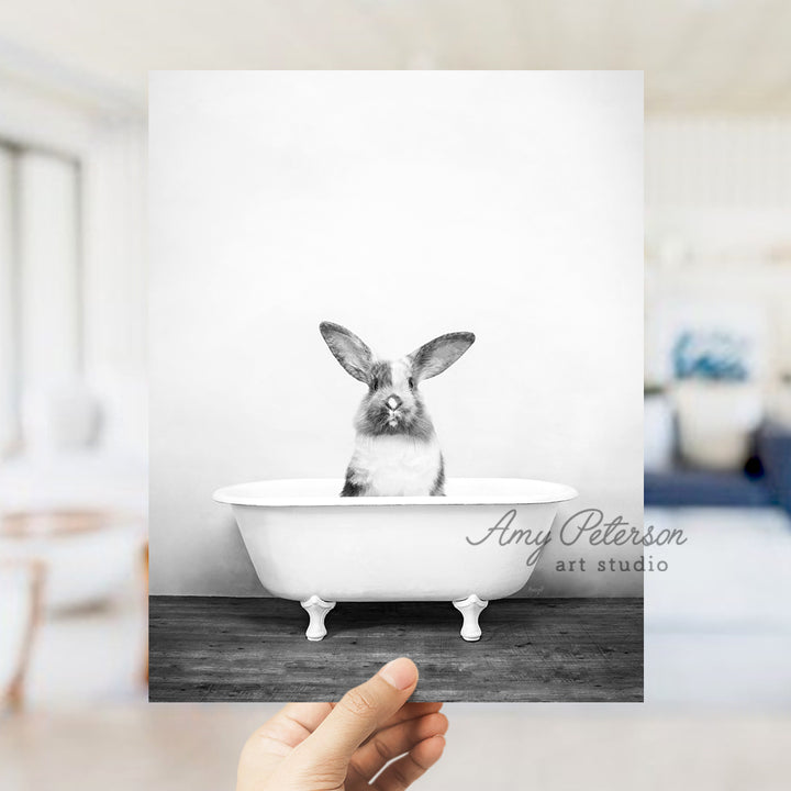 a person holding up a card with a picture of a rabbit in a bathtub