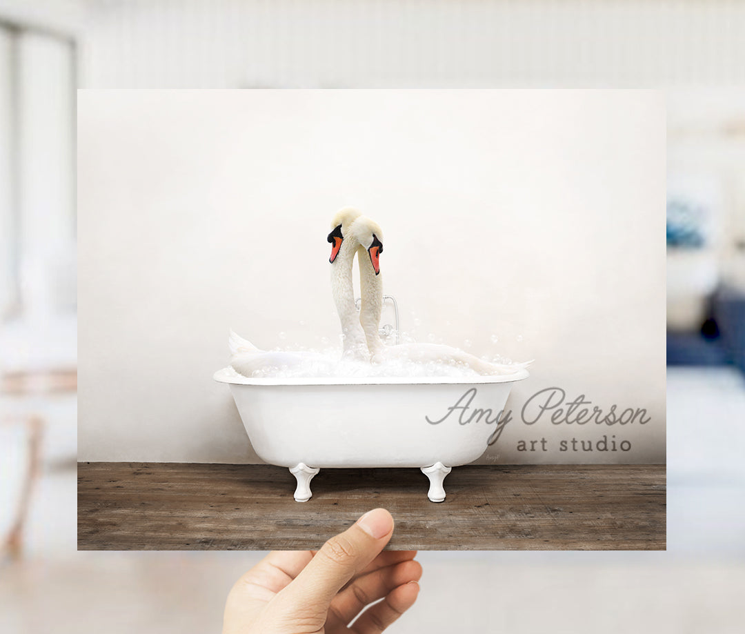 a person holding up a picture of two swans in a bathtub