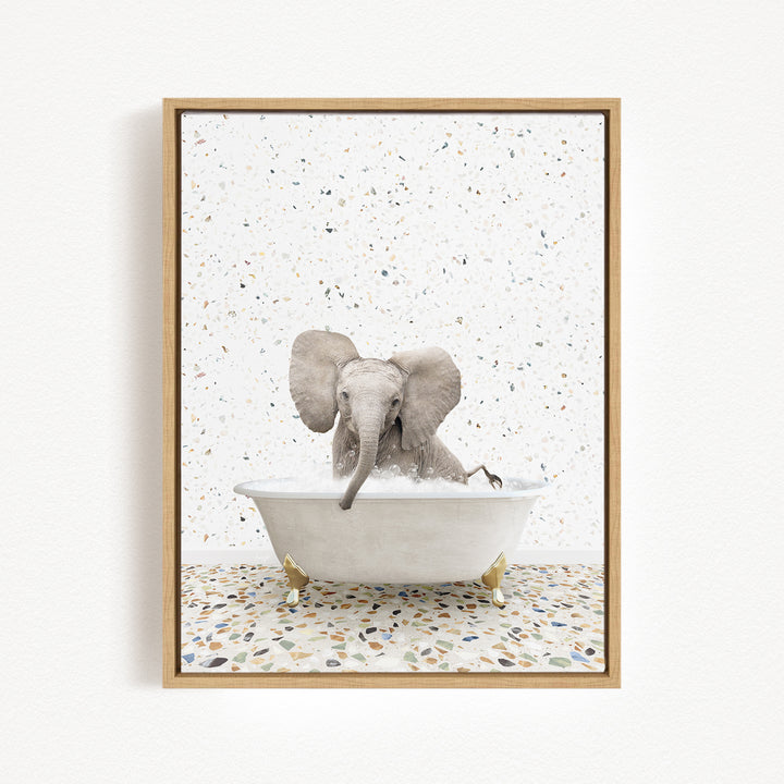 A baby elephant sitting in a white bathtub filled with water, surrounded by a speckled tiled floor.