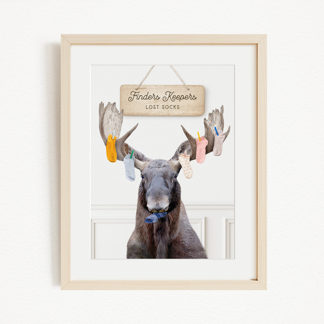 A framed image of a moose with a sign that says "Finders Keepers" hanging above it.