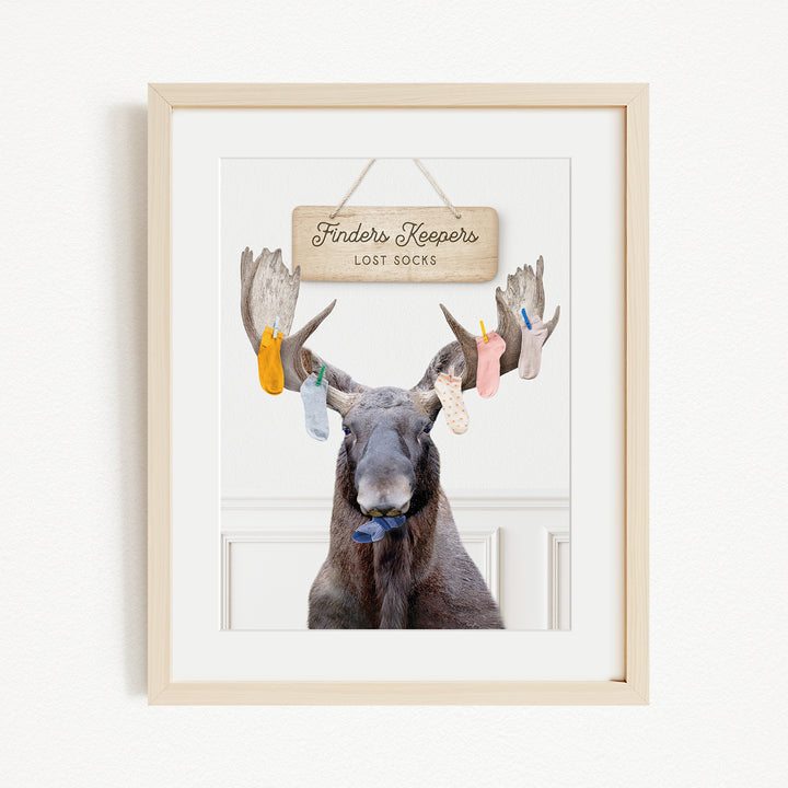 A framed image of a moose with a sign that says "Finders Keepers" hanging above it.