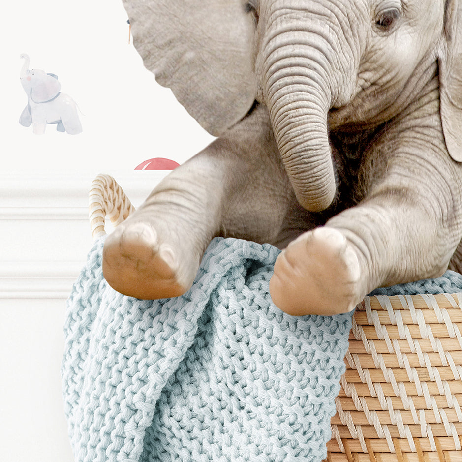 a stuffed elephant sitting on top of a basket